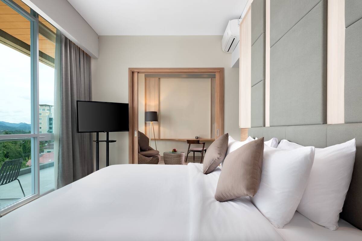 A hotel room with a large bed, a TV, a desk, and a chair.