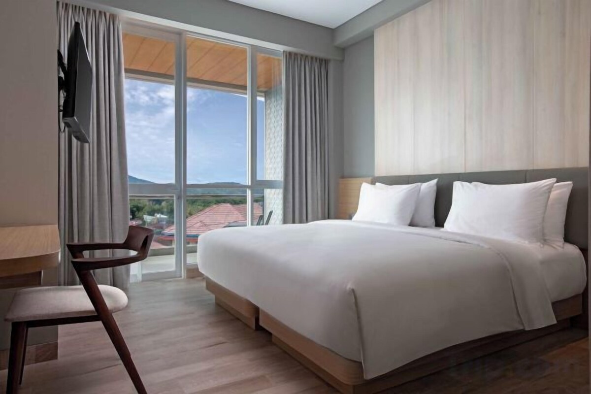 A hotel room with a large bed, a desk, and a chair.