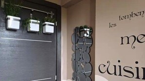 Un mur orné d’un élément décoratif en métal et de trois plantes en pot.
