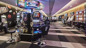 Un casino avec des machines à sous, un bar et un sol à carreaux.