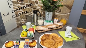 Une table de petit-déjeuner avec une variété d’aliments, notamment du pain, des viennoiseries, des fruits et des boissons.