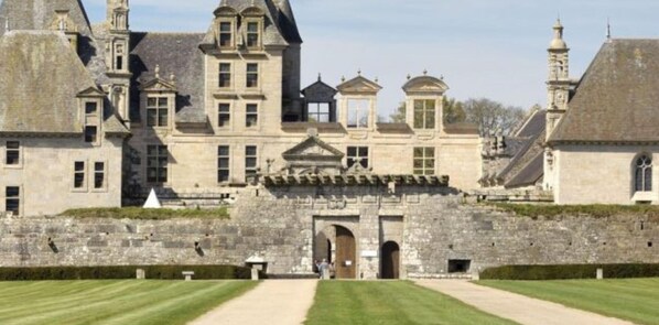 Un bâtiment historique à la façade symétrique, doté de grandes fenêtres et d’une entrée centrale.