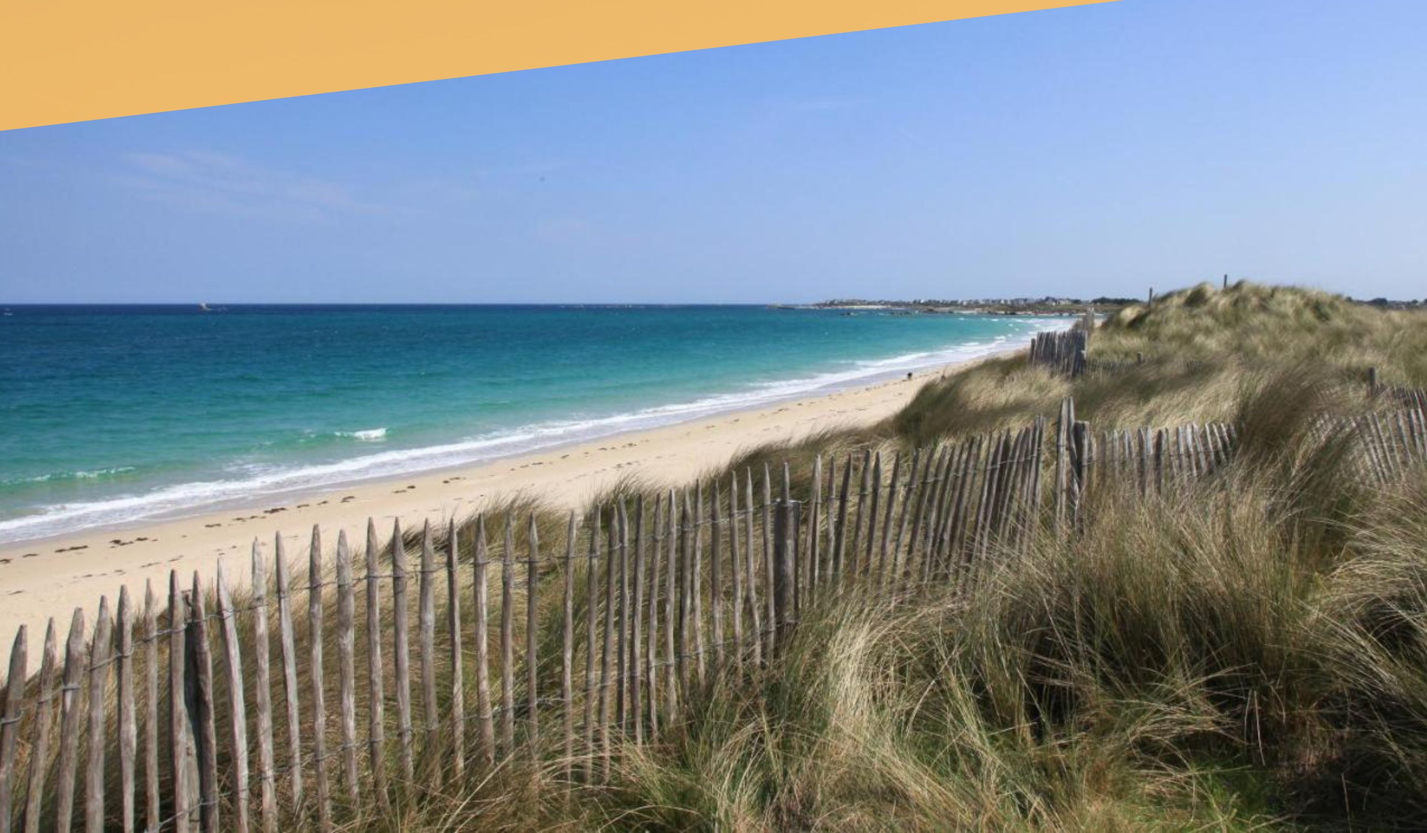 Una spiaggia con una recinzione in legno e una vista aperta sull'oceano.