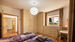 A bedroom with two beds, a desk, a chair, a window with curtains, and a hanging light fixture. - Spacious Apartment “Lafreid Algund” near Merano with Mountain View, Wi-Fi & Garden (Algund)