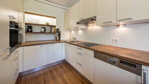 A modern kitchen with white cabinets, a wooden countertop, a built-in dishwasher, and a coffee maker. - Spacious Apartment “Lafreid Algund” near Merano with Mountain View, Wi-Fi & Garden (Algund)