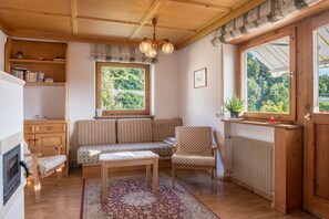 Una habitación acogedora con techo de madera, un banco, una silla, una mesa y una ventana con vista a la vegetación.