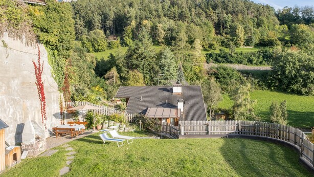 A house with a sloped roof, a fenced yard, and a view of a forested hill.