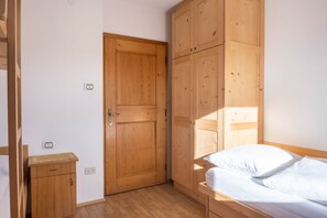 Un dormitorio con un armario de madera, una cama individual y una mesita de noche pequeña.