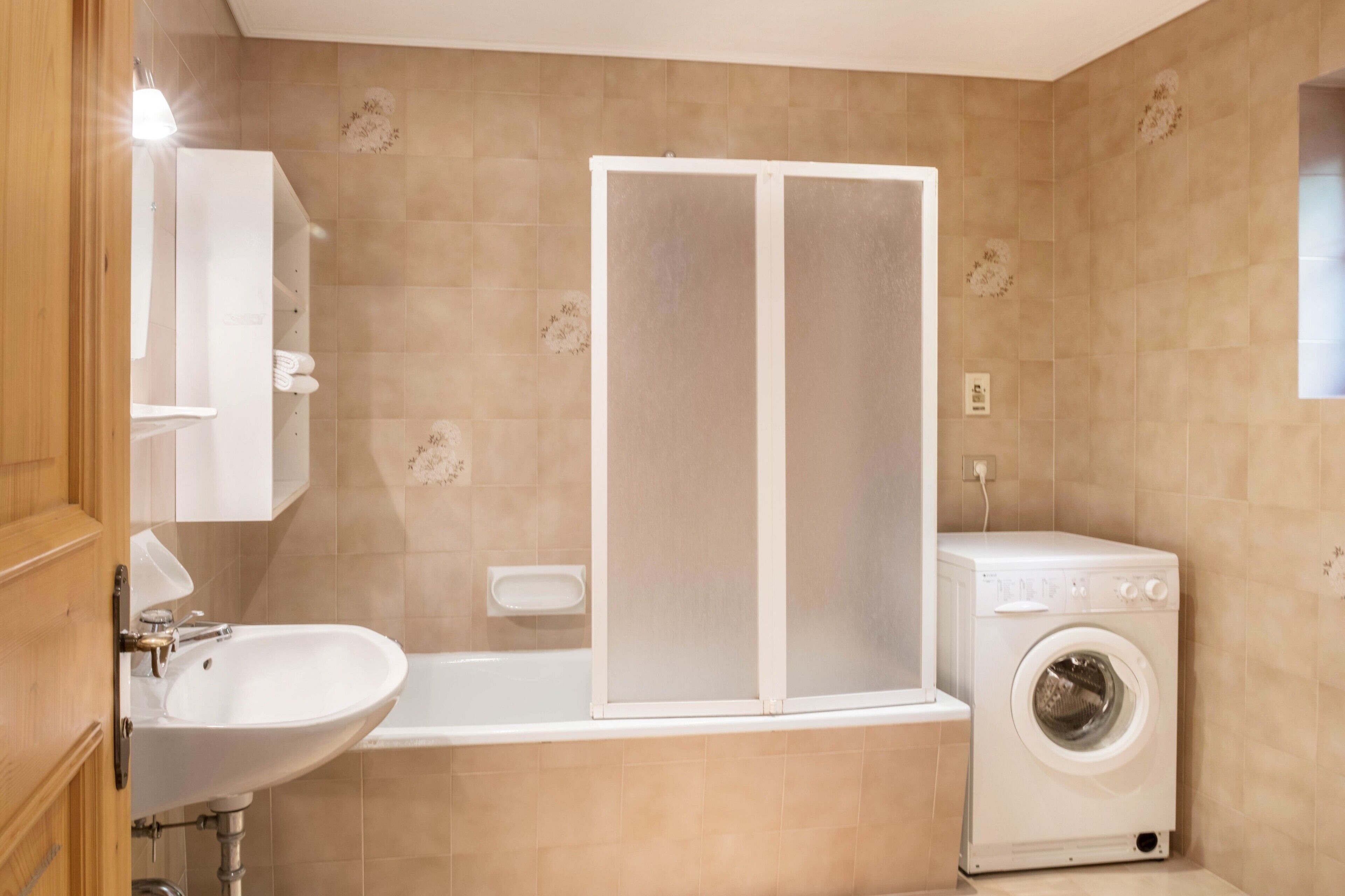 Une salle de bain équipée d’un lavabo, d’une douche et d’un lave-linge.