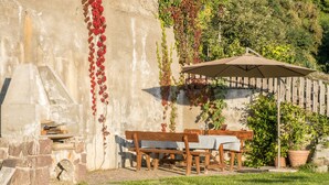 Un'area salotto esterna con tavolo e sedie, un muro in pietra e una recinzione in legno.