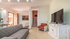 Una sala de estar con un sofá, un televisor, un mueble y una escalera que lleva a otra habitación.