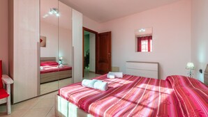 Un dormitorio con una cama grande, un espejo, un armario y una ventana pequeña.