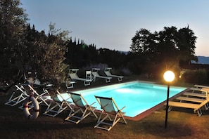 A swimming pool with lounge chairs and a light post.