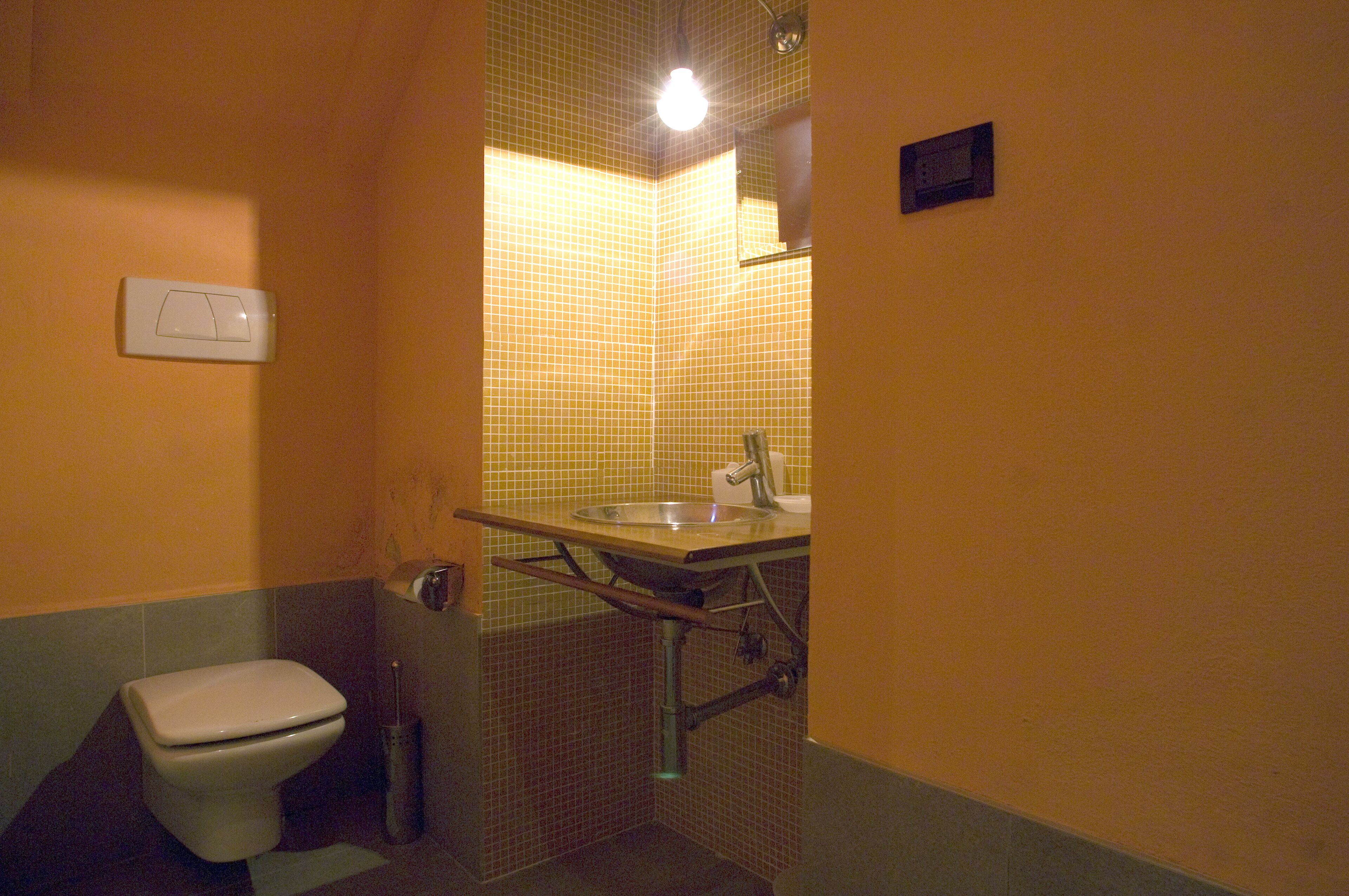 A small bathroom with a toilet, sink, and shower.