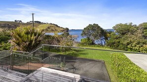 Une terrasse extérieure moderne, dotée de rampes en verre, qui offre une vue imprenable sur un paysage vallonné et un lac.