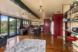 A spacious living area with a large window, a fireplace, and a dining area with a table and chairs.
