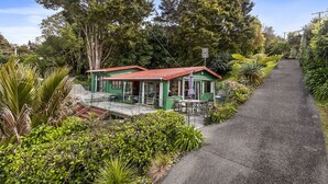 Un petit bâtiment doté d’un toit végétalisé et d’un patio, entouré d’une végétation luxuriante et d’arbres.
