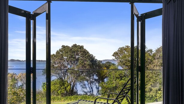 Un balcon avec une chaise en métal, donnant sur un lac et des arbres.