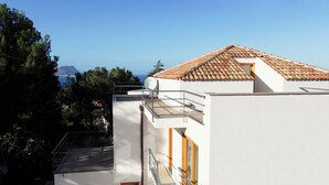 Un edificio moderno con tejado de baldosas, antena parabólica y vista al mar.