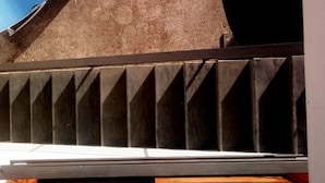 Un interior moderno con pared de concreto, banca de madera y baranda de metal.