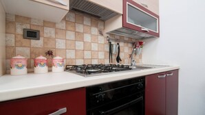 Eine Küche mit Gasherd, Backofen und Mikrowelle über der Arbeitsfläche. Auf der Arbeitsplatte stehen drei dekorative Behälter.
