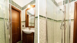 Ein Badezimmer mit Holztür, Waschbecken, Spiegel und Duschkabine mit Glastüren.