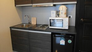 A compact kitchen with dark wood cabinets, a stainless steel sink, a microwave, a coffee maker, and a small refrigerator. - Park Lane Condo F4 R419 (Pattaya)