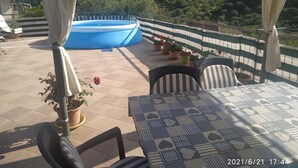 Eine Terrasse mit Pool, Sitzgelegenheit im Freien und Blick auf eine Hügellandschaft.