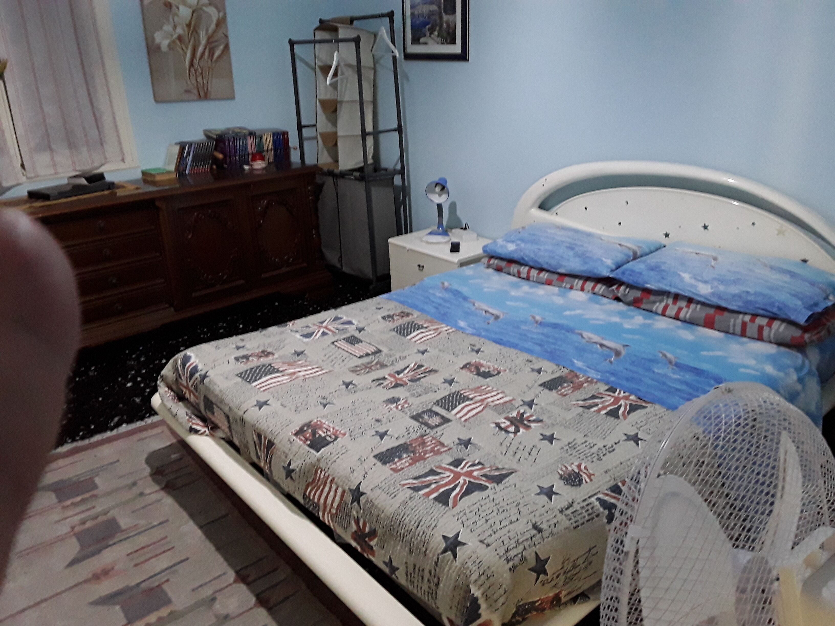 A bedroom with a bed, a dresser, a nightstand, and a window with curtains.