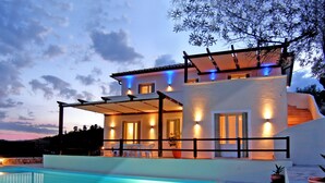 Una casa moderna con piscina, un patio coperto e vista sul paesaggio circostante.