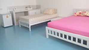 A bedroom with a bed, a desk, and a small cabinet.