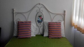 A bed with a white headboard, two striped pillows, and a green bedspread.