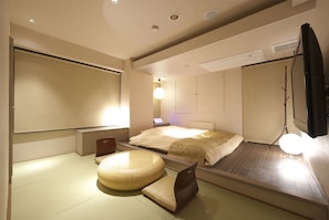 A modern hotel room with a bed, a round seating area, a desk, and a TV. - Jyubankan - Adults Only (Yokohama)
