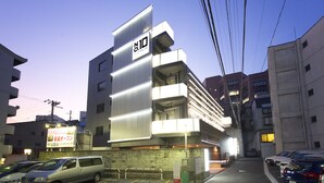A modern building with a prominent '10' sign, multiple floors, and a parking area in front. - Jyubankan - Adults Only (Yokohama)