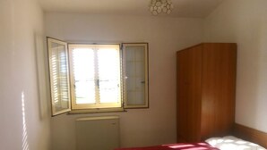 A bedroom with a bed, a wooden wardrobe, and a window with blinds. - Single Room for Rent With Private Bathroom (Montenero di Bisaccia)