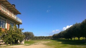 A building with a balcony, a gravel path, and trees in the background. - Single Room for Rent With Private Bathroom (Montenero di Bisaccia)