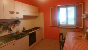 A compact kitchen with white cabinets, a gas stove, and a window with blinds. - Single Room for Rent With Private Bathroom (Montenero di Bisaccia)