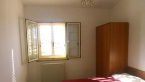 A bedroom with two beds, a wooden wardrobe, and a window with blinds. - 4 Seater Room for Rent With Private Bathroom and Wifi - Molise (Montenero di Bisaccia)