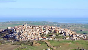 An aerial view of a coastal town with a prominent tower, surrounded by densely packed buildings and green fields. - 4 Seater Room for Rent With Private Bathroom and Wifi - Molise (Montenero di Bisaccia)