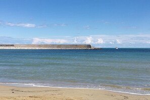 Ein Strand mit einer Betonmauer und einem Schiff in der Ferne.