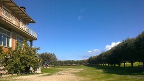 A building with a balcony, surrounded by a grassy area and trees. - 6-bed Room for Rent With Private Bathroom - Molise (Montenero di Bisaccia)