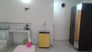 A small, clean room with a white table, a yellow cabinet, a white sofa, and a dark wardrobe. - Room-asia Don Mueang Bangkok Condominium (Pak Kret)