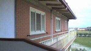 A balcony with white railings and shutters, overlooking a grassy area. - Triple Room for Rent With Private Bathroom in Molise - Wifi (Montenero di Bisaccia)