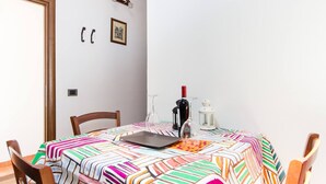 A dining area with a table set for two, a laptop, wine glasses, and a bottle. - Appartamento In Centro Siracusa (Syracuse)