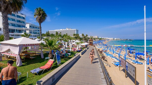 A beachside walkway with sun loungers, umbrellas, and a massage tent.