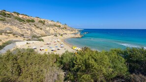 Ein Strand mit klarem türkisblauem Wasser, felsigen Klippen und üppiger Vegetation.