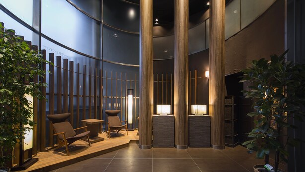 Un vestíbulo moderno con mostrador de recepción, zona de estar y altas columnas de madera.