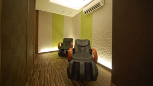 Un pasillo con dos sillones de masaje, piso de madera y paredes verdes.