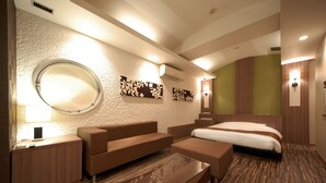 Una habitación de hotel moderna con un espejo redondo, un sofá, una cama y una mesita.
