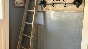 A wooden ladder leaning against a wall with a rustic metal coat rack. - Compass Cottage in Historic Glen Rose (Glen Rose)